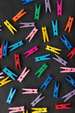 Siyah arka planda kaotik bir şekilde farklı renkte mandallar. Üst Manzara. Dikey çerçeve