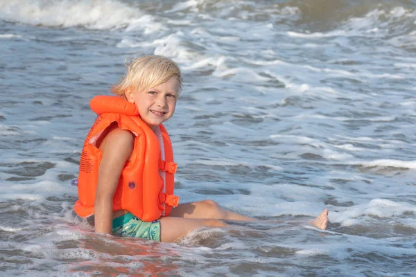 Happy Fair Haired Boy Inflatable Swimming Vest Sits Seashore Waves — Stock Photo, Image
