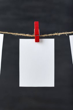 İpte mandal olan beyaz, boş bir kart. Uzayı kopyala, Mockup.Siyah arkaplan.