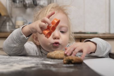 Tatlı sarışın çocuk kurabiye pişirmeye yardım eder. Küçük kız hamurdan zencefilli ekmek yapar..