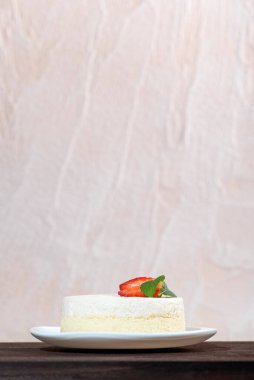 Çilekli cheesecake beyaz tabakta, arka planda. Dikey çerçeve.