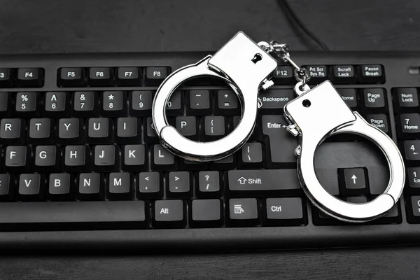 Handcuffs on the keyboards. Internet scam concept. Internet fraud