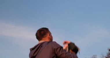 Father throws up and catches his young daughter. Happy father. Blue spring sky in the background.