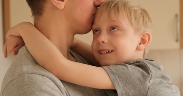 Boy tries to cheer up his frustrated father. Son sits in his arms and hugs his father. Home furnishings — Stok video