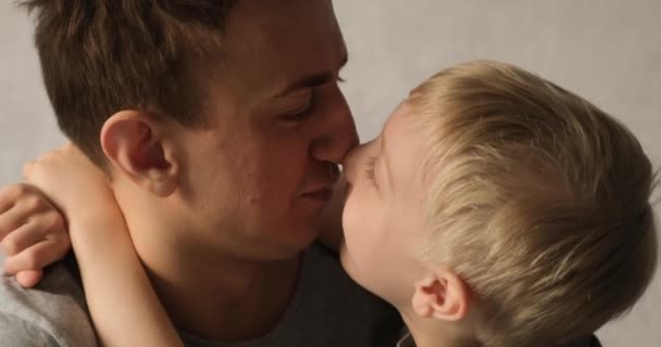 Vater und Sohn reiben sich an der Nase, der Junge erzählt etwas. Kind umarmt Papa. Zärtlichkeit zwischen Eltern und Kind — Stockvideo