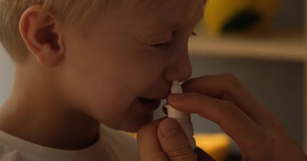 Mão das mulheres injeta um spray nasal para um menino loiro. Procedimentos de higiene em casa. Luz natural. Close-up — Vídeo de Stock