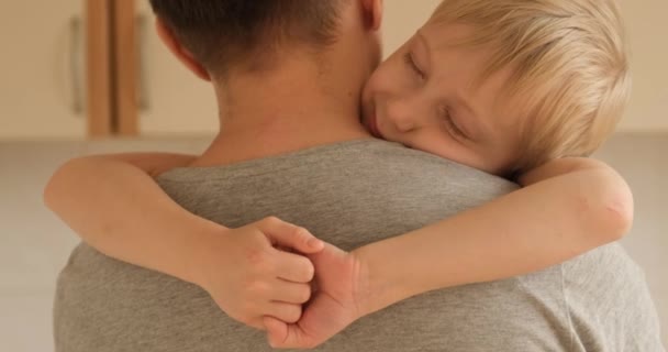 Un niño dormido abraza a su padre. El hijo pone su cabeza sobre el hombro de su padre. Padre e hijo reconciliados — Vídeos de Stock