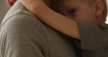 Hüsrana uğramış çocuk babasına sarılıyor. Babasının kollarında üzgün bir oğul. Yakın bağ, güven. Yakın plan portre