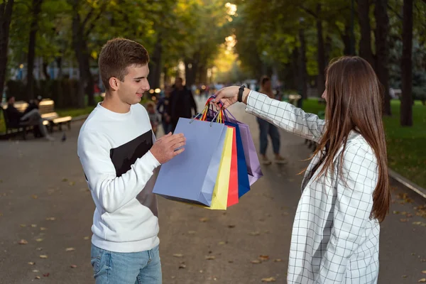 Girl Brags Shopping Her Boyfriend Holds Shopping Bags Her Hands — Stock Photo, Image