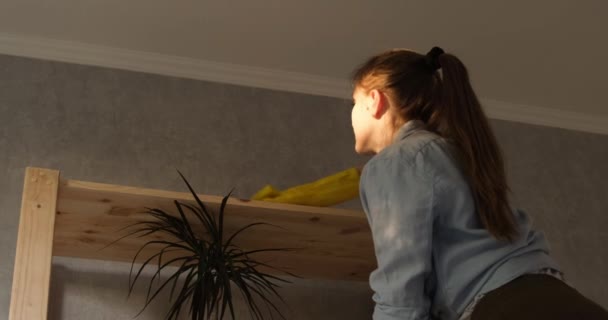 Το κορίτσι σκουπίζει σκόνη από το ράφι, ράφι. Νεαρή γυναίκα καθαρίζει το σπίτι. Αργή κίνηση. Φυσικό φως. — Αρχείο Βίντεο