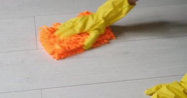 Eldivenli temizlikçi kadın mikrofiber bezle yerleri yıkıyor. Parke zeminini temizliyorum. Yapışma servisi.