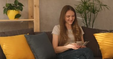 Şaşırmış yüzlü genç bir kadın para sayıyor. İşte nakit prim. Maaşlar yükseldi. İyi tavsiye.