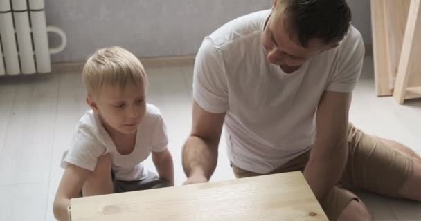 Dad and little son paint table, curbstone. Child helps his father. Daylight. — Stock Video