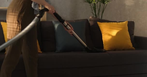 Ragazza aspira il divano. Pulizia divano dalla polvere. La casalinga pulisce la casa. Servizio di pulizia. — Video Stock
