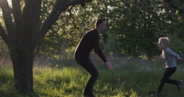 Oğlu babasına koşuyor. Mutlu çocuk babasının ellerine koşuyor. Gün batımı