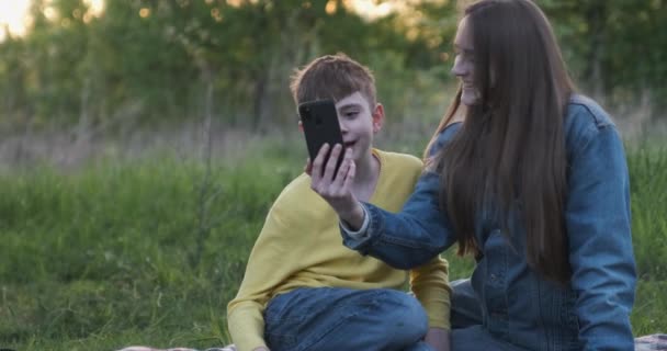 Moeder en zoon knuffelen in de natuur en nemen selfie aan de telefoon. — Stockvideo