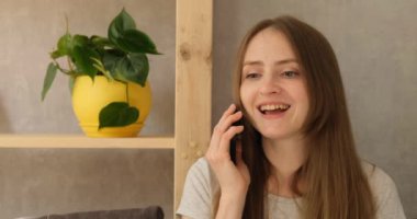 Telefonla konuşan ve gülümseyen kız. Genç bir kadın çağrıya cevap verir, konuşur, olumlu bir şekilde başını sallar, evet cevabını verir..