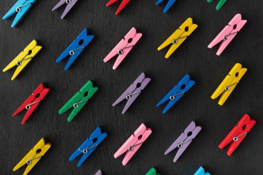 Siyah arkaplandaki çok renkli mandalların üst görüntüsü. Seçim çeşitliliği.