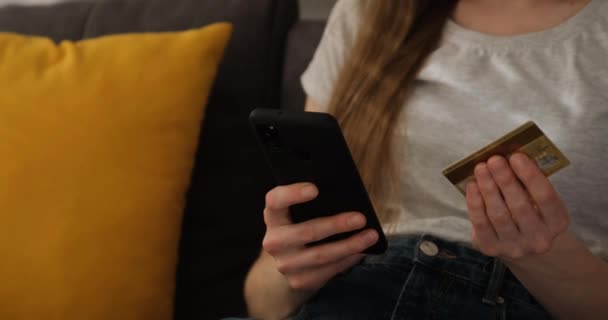 A nő beírja a telefonba a hitelkártya számát. A lány telefonon fizeti a számlákat. Online vásárlás — Stock videók