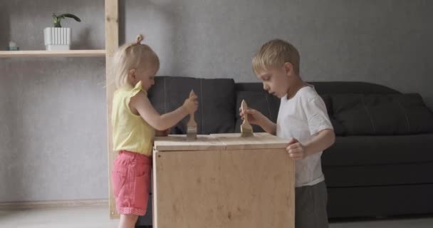 Anak-anak dengan lembut melukis meja putih. Anak laki-laki dan gadis melakukan pertukangan kayu. Gerakan lambat — Stok Video