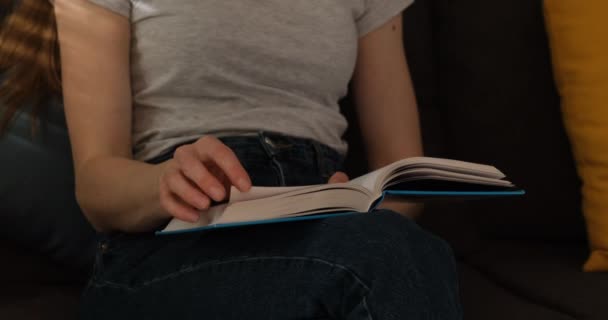 Young woman reads book. Girl turning pages of paper book. Close up. Slow motion. — Stock Video