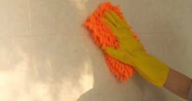 Lateks eldiven, banyo duvarını mikrofiber bezle yıkıyor. Tuvaleti temizliyorum.