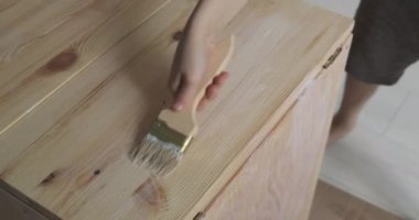 Erkekler masayı fırçayla boyarlar. Çocuk koruyucu kaplama uyguluyor. Marangozluk işi.