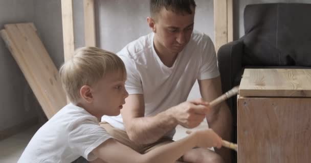 A fiatal apaács megtanítja a fiát, hogyan dolgozzon a fával. A fiú segít az apjának a műhelyben.. — Stock videók