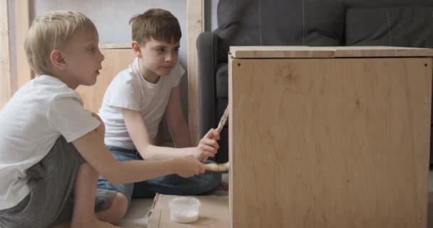 Due fratelli riparare e dipingere superficie di legno. Ragazzi aiutano nel laboratorio di falegnameria. — Video Stock