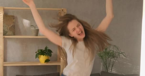 Χαρούμενο χαρούμενο κορίτσι γελάει και πηδάει. Νεαρή γυναίκα χορεύει στο σαλόνι. Αργή κίνηση. Φως ημέρας — Αρχείο Βίντεο