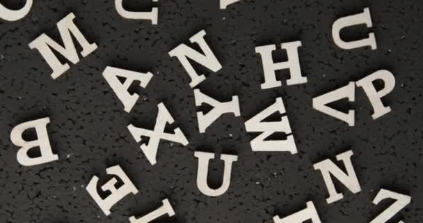 Siyah zemin üzerinde İngiliz alfabesinin beyaz harfleri dairesel rotasyonda hareket eden kaotik bir şekilde dağılmış durumda.. — Stok video