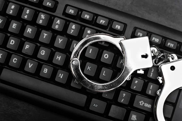 Keyboard and handcuffs top view. Internet scam concept. Internet fraud