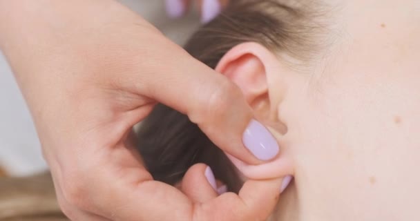 Massaggiatore massaggi lobo dell'orecchio giovane donna. Massaggio alla testa. Impatto sui punti attivi sulle orecchie. — Video Stock