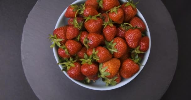 Vista de arriba hacia abajo del plato con fresas frescas sobre fondo gris. Rotación de vídeo. Movimiento de bucle. — Vídeos de Stock