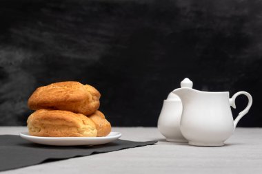 Homemade eclairs and creamer. Traditional French eclairs. Gray background.