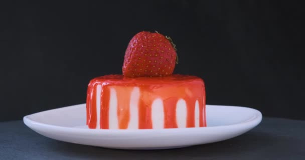 Obstkuchen garniert mit frischen Erdbeeren. Dessert auf Untertasse auf schwarzem Hintergrund. Rotierendes Video. — Stockvideo