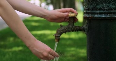 Çocuk antik bir sokak vincini açar ve ellerini yıkar. Açık deniz musluğu. Sokaktaki çeşme..