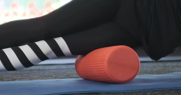 Kız kalça kaslarını miyofasyal rulo ile yoğuruyor. Spor kıyafetli kadın köpük silindir kullanıyor.. — Stok video