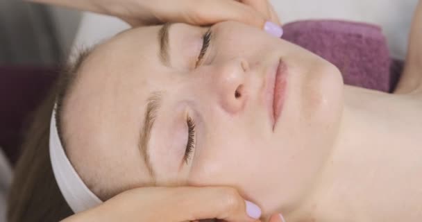 Modélisation, drainage lymphatique massage facial. Jeune femme dans le salon de beauté spa à la séance de construction du visage. Gros plan — Video