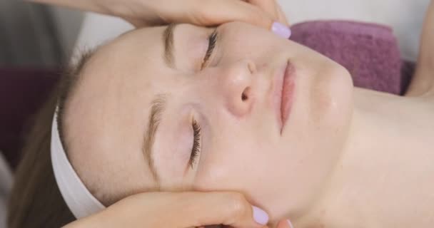 Modelado, masaje facial de drenaje linfático. Mujer joven en el salón de spa de belleza en la sesión de facebuilding. De cerca. — Vídeo de stock