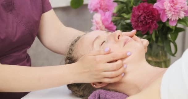 Esteticista faz modelagem de massagem facial para paciente jovem. Edifício Facebook. Tratamento de spa para pele perfeita — Vídeo de Stock