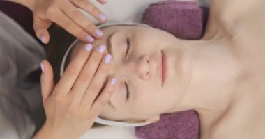 Terapist yüz masajına başlamadan önce hastalara yağ sürüyor. Yüz geliştirme prosedürleri. Kapatın. Üst görünüm.