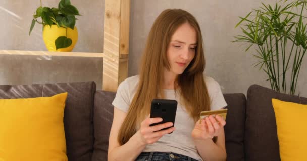 Jonge vrouw doet aankopen via internet via de telefoon, betalen met een creditcard. Online winkelen. — Stockvideo