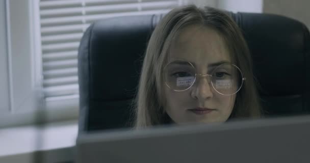 La mujer con gafas mira al monitor y no está contenta con algo. Contable en funciones durante el trabajo. — Vídeos de Stock
