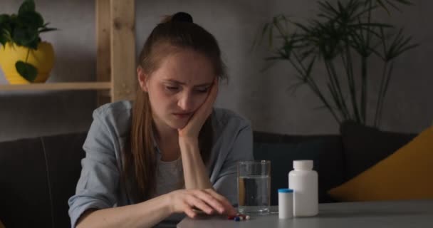 Depressive junge Frau trinkt Tabletten. Traurig müdes Mädchen zweifelt an Einnahme von Pillen. — Stockvideo