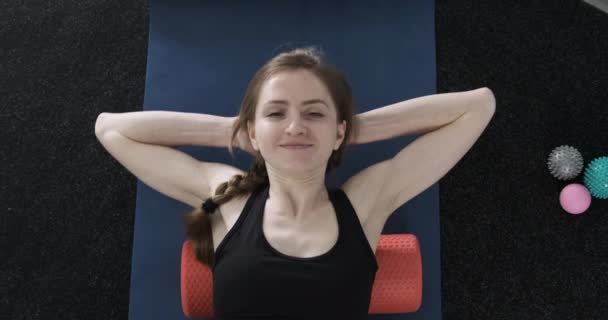 Mujer joven amasa los músculos de la espalda con un rodillo de masaje para yoga. Rodillo para fisioterapia. MFR. Liberación miofascial. — Vídeo de stock