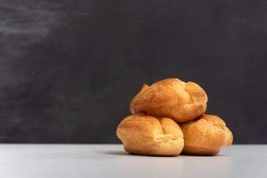 Profiteroller, börekler, eklerlerin yan görünüşü. Üç iştah açıcı profiterol. Gri arkaplan