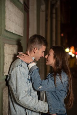 Gülümseyen gençler sokakta sarılırlar. Akşam randevusu, aşık genç bir çift. Güzel kız bir erkeği kucaklıyor. Gece şehri.