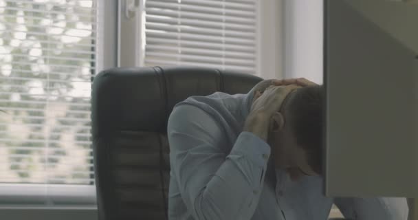 Kantoormedewerker wordt nerveus tijdens serieus werk. Jongeman in een bureaustoel aan het bureau. — Stockvideo