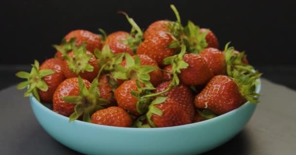 Plato con fresas frescas y apetitosas sobre fondo negro. Baya roja estacional. Rotación de vídeo. Movimiento de bucle. — Vídeos de Stock
